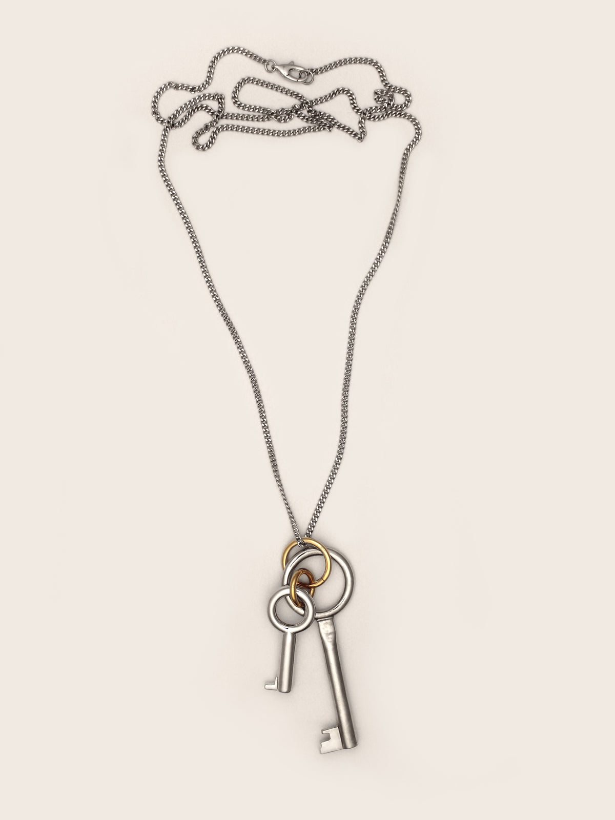 Laura Lombardi Permesso Necklace, a silver-toned key pendant necklace with a large and small silver key charm and gold accent ring, shown on a neutral background.