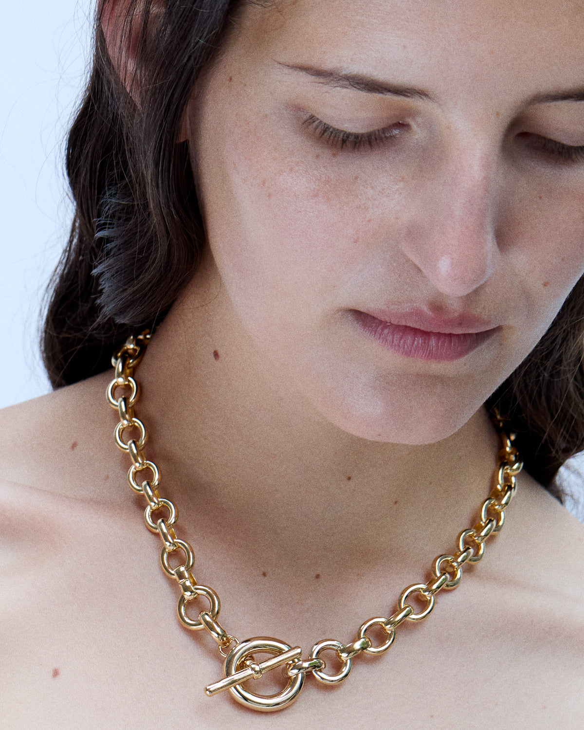 Person wearing Laura Lombardi gold Portrait Necklace with toggle clasp facing front.