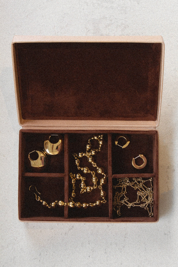 Laura Lombardi beige jewelry box with brown plush lining with gold necklaces and earrings inside.