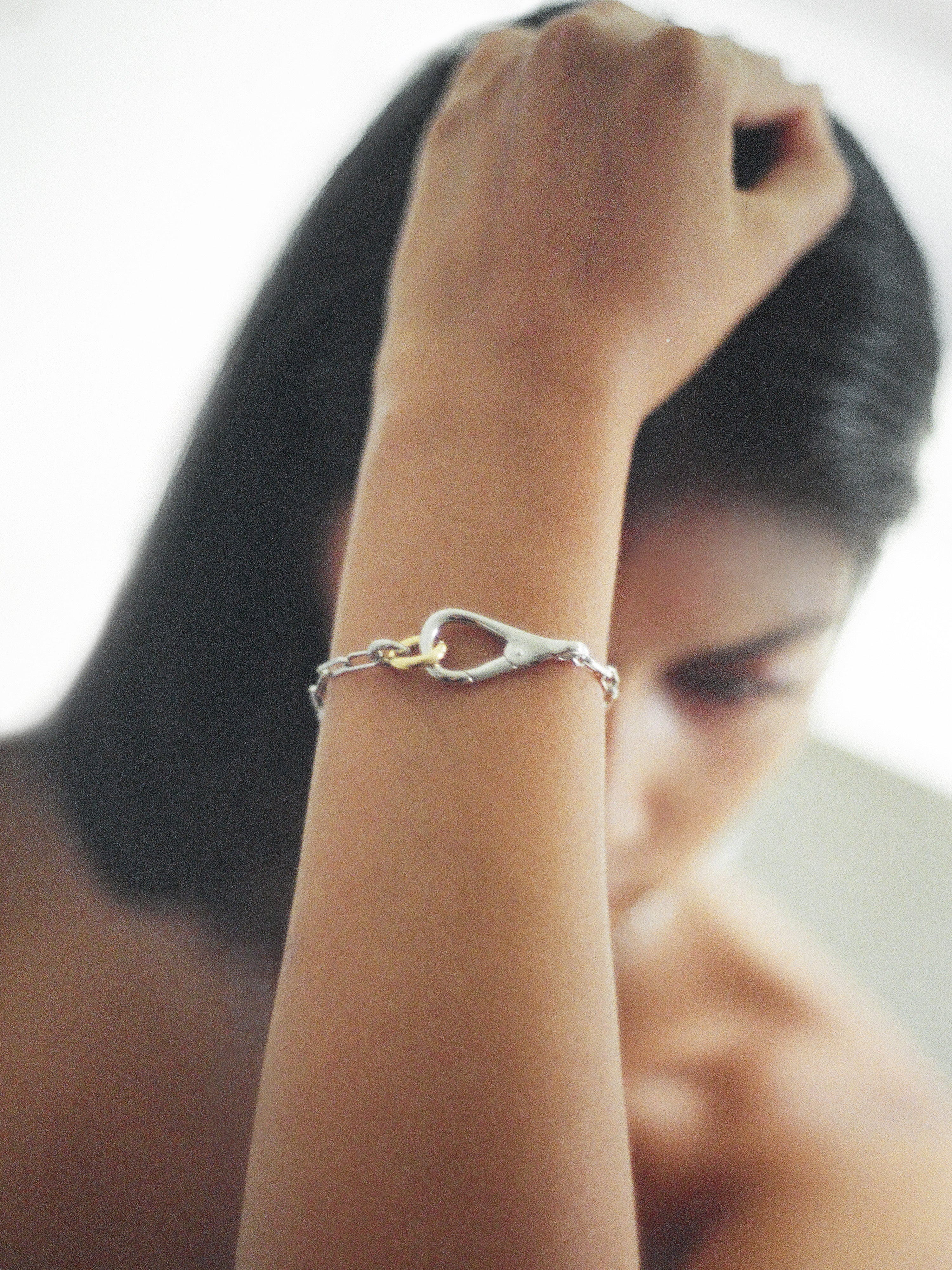 Two Tone Frena Bracelet, a silver-toned chain bracelet with a silver toggle clasp and gold jump ring, displayed on a neutral background.