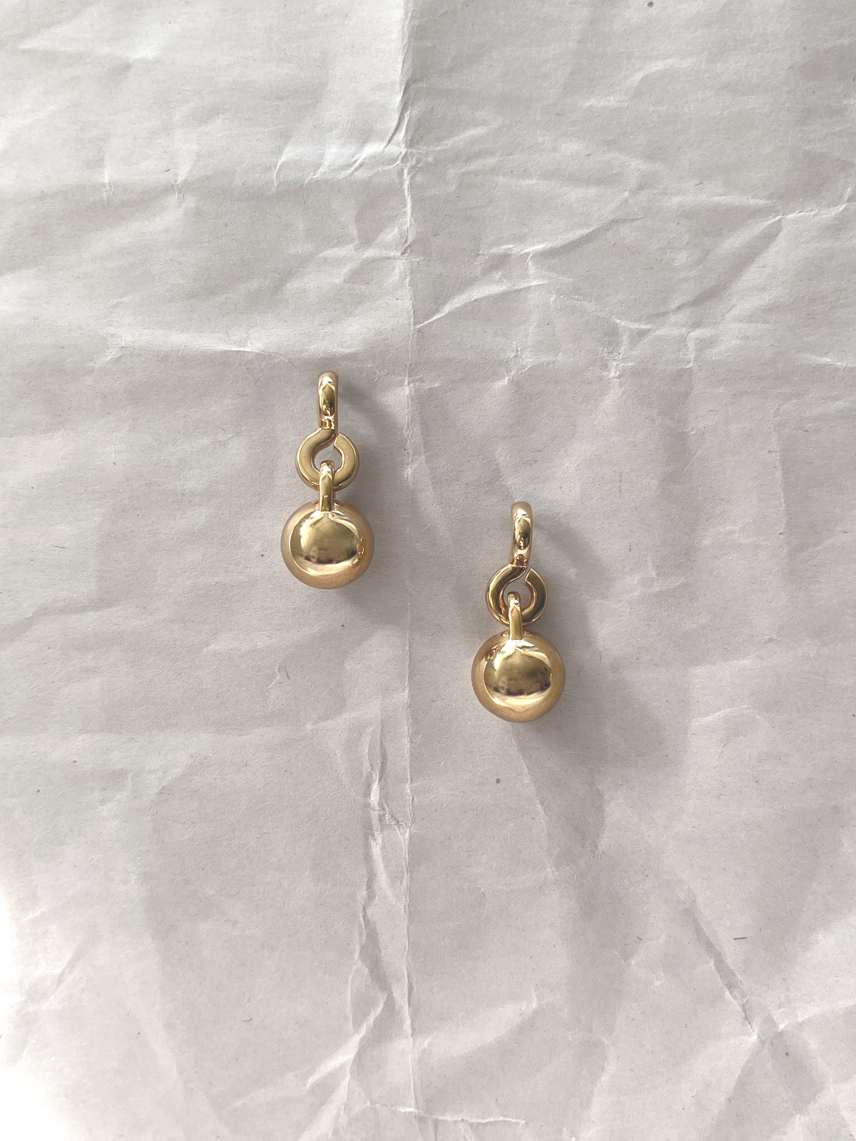 Laura Lombardi gold Gioca drop earrings on a white paper background.