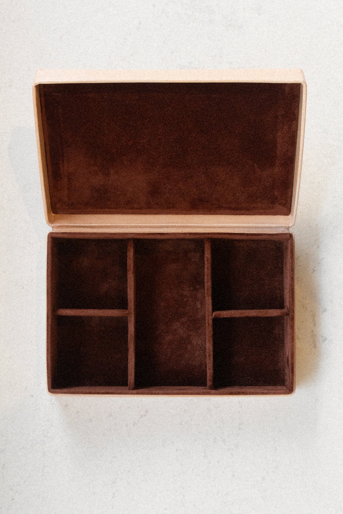 Interior of Laura Lombardi jewelry box, with brown plush lining against a neutral background.