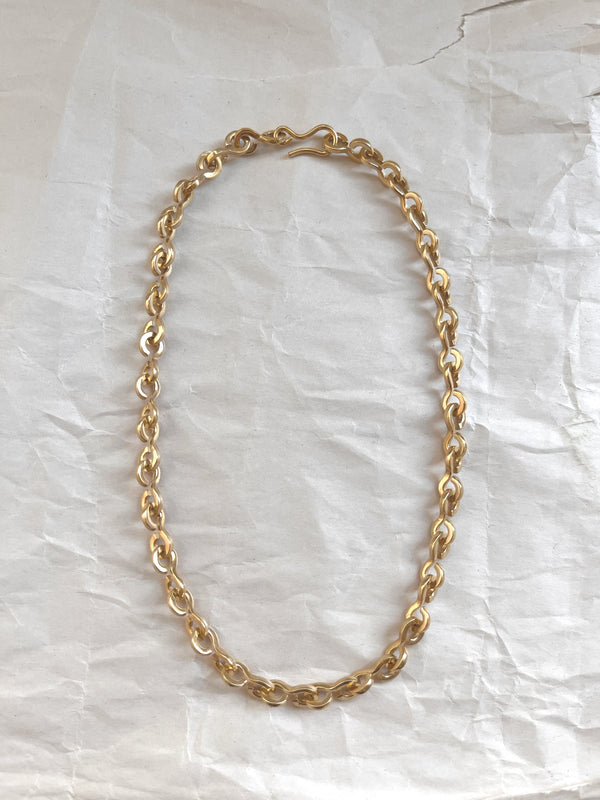 Laura Lombardi gold Nuova chain necklace on a white paper background.
