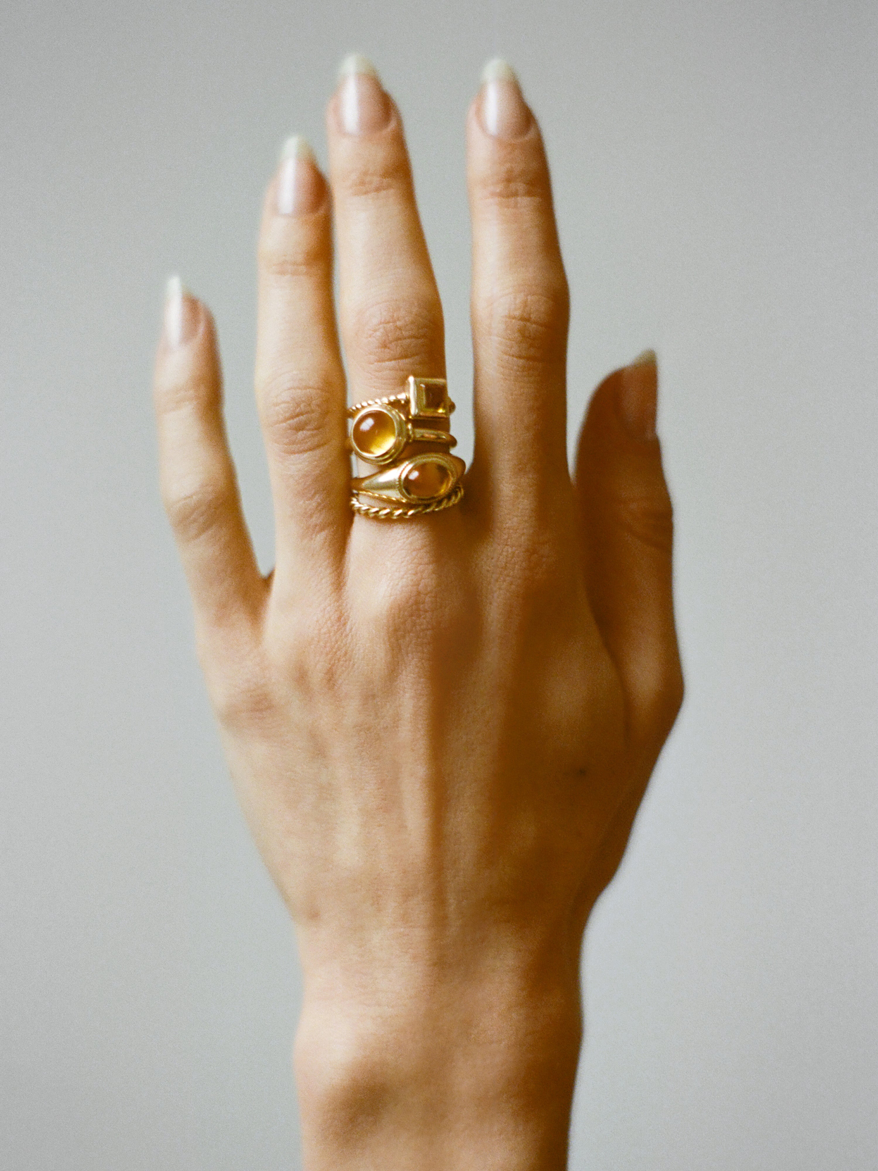 Model wearing Laura Lombardi gold Ginerva Ring, Sfera Ring, Quadro Ring and Twist Ring with Citrine stone.