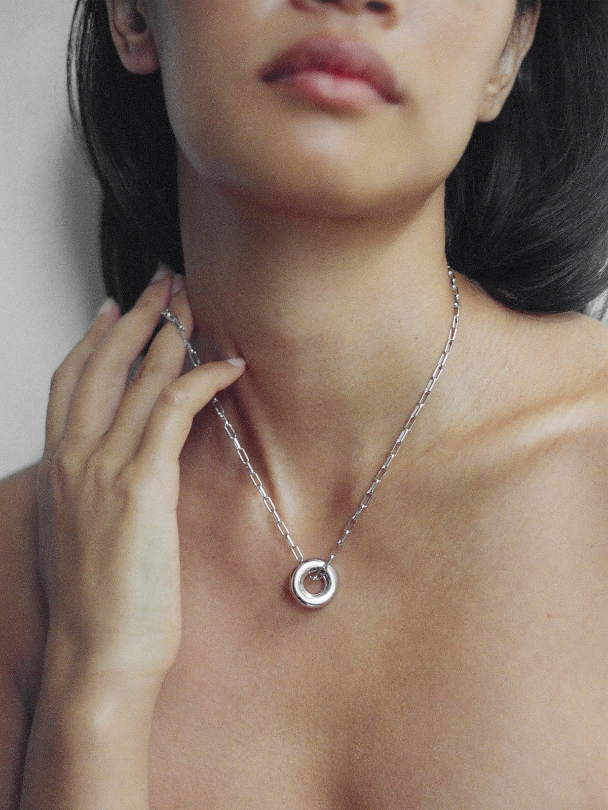 A close-up of a model wearing the Silver Single Moneta necklace with a round pendant on a silver chain